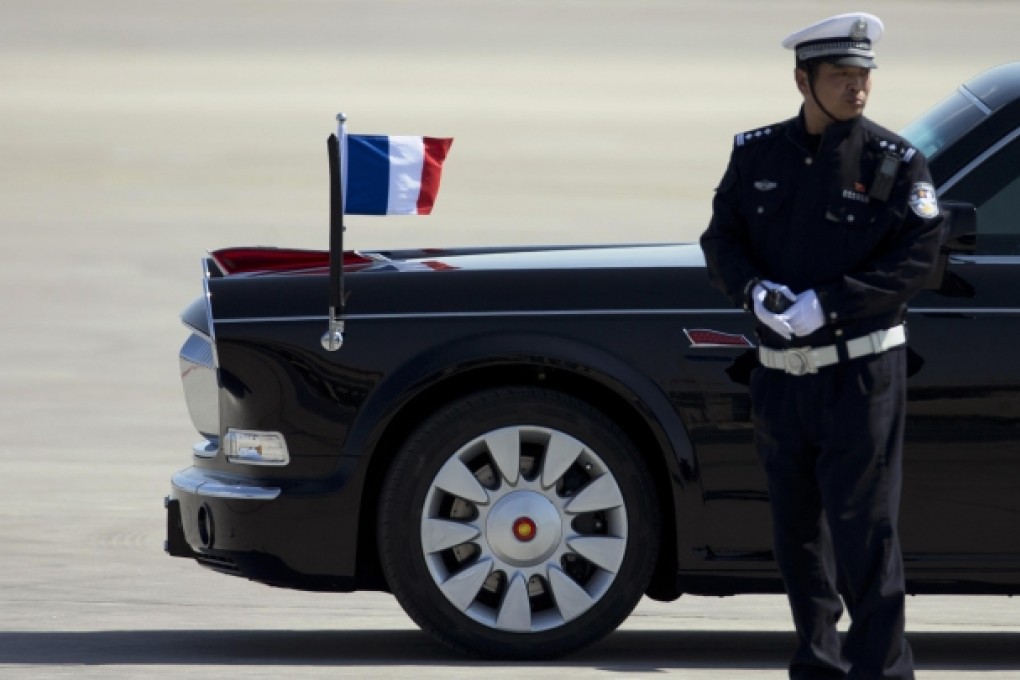 A Red Flag carrying the French president and his wife passes a policeman as it leaves Beijing Capital International Airport for the city on April 25 this year. Photo: AP