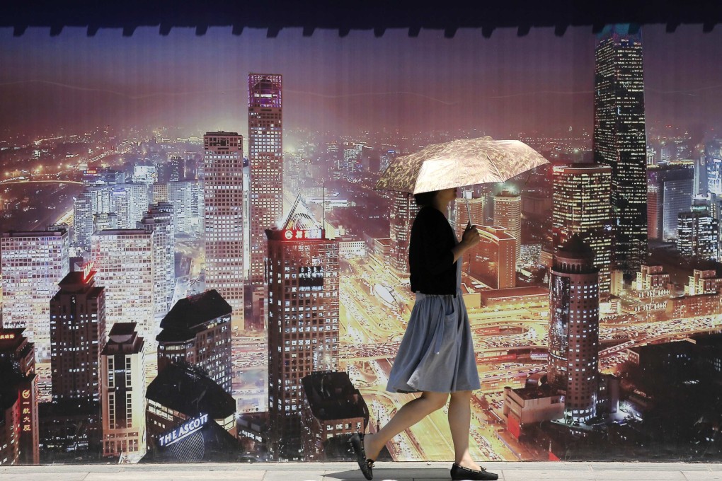A woman walks past a wall bearing an image of Beijing's skyscrapers outside a construction site for a new residential complex in Beijing June 18, 2013. Photo: Reuters