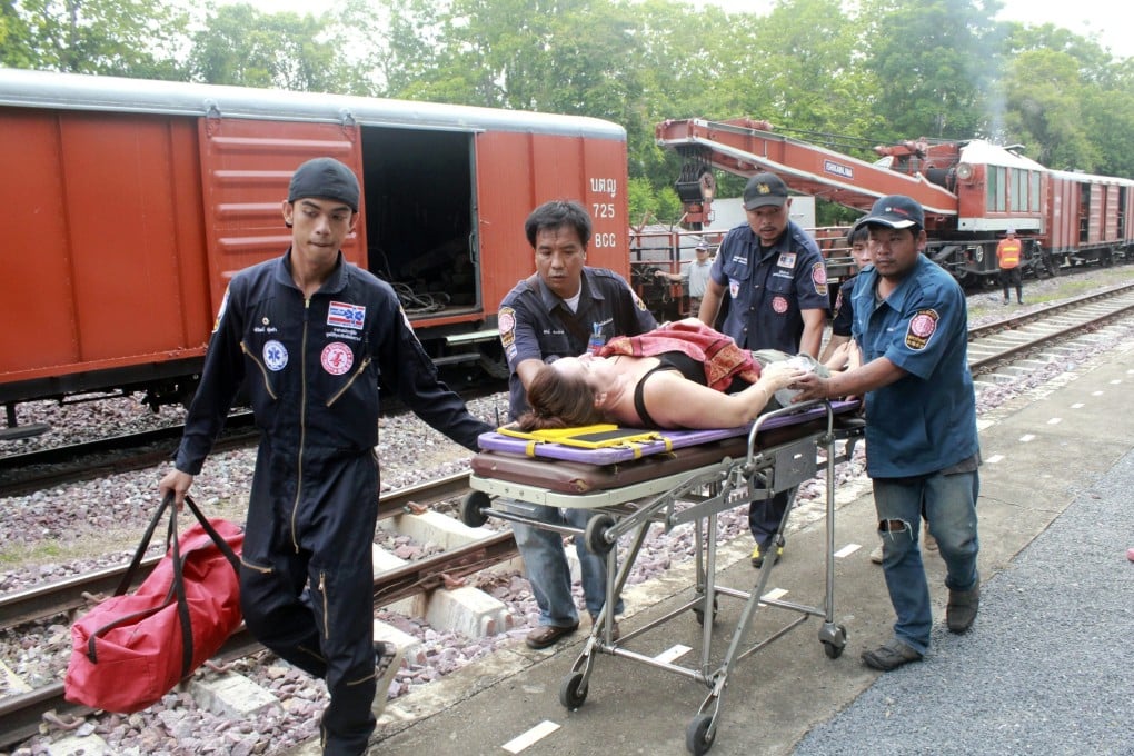 Thai rescue workers give medical treatment to an injured foreign tourist at a railway after a passenger train derailed in Den Chai district of Phrae province in northern Thailand. Photo: EPA