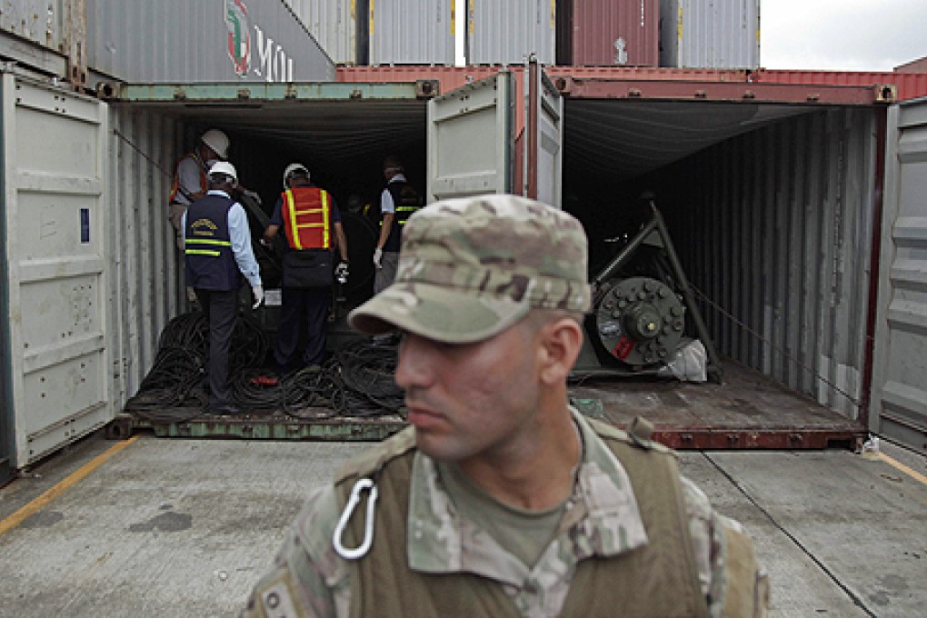 A police officer stands guard as investigation officers look inside a recently opened container holding military equipment aboard a North Korean freighter. Photo: AP