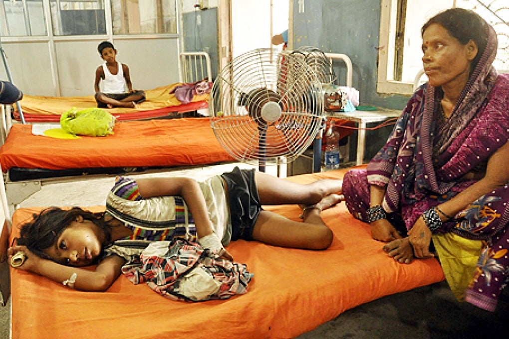 An Indian woman sits beside a child who fell sick after eating a free school lunch, at a hospital in Patna, India, on Thursday. Photo: AP