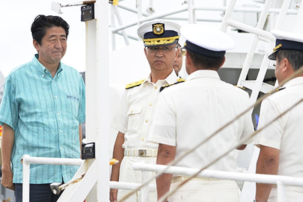 Japan's Prime Minister Shinzo Abe (left) smiles as he meets officers of Japan Coast Guard at his inspection tour on patrol ship Ishigaki in Ishigaki, southern Japan, on Wednesday. Photo: AP
