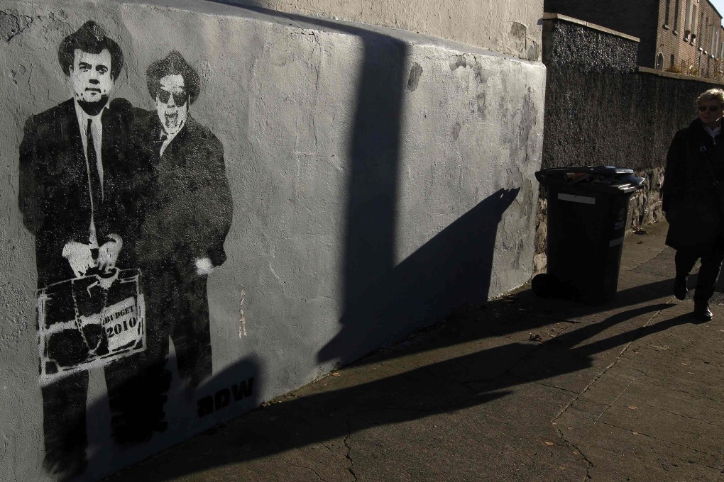 A woman passes graffiti lampooning Brian Lenihan and Brian Cowen, who were finance minister and prime minister in 2010, when Ireland had to be bailed out after its banking sector collapsed. Photo: Reuters