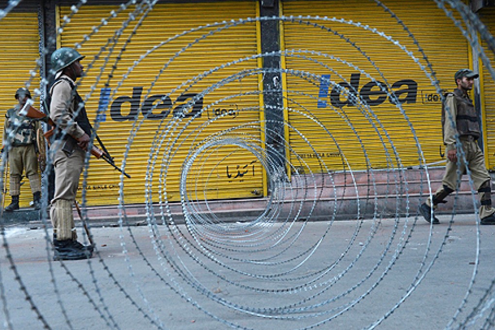 An Indian paramilitary trooper stands guard near a barbed wire fence during a curfew imposed on the Kashmiri summer capital in Srinagar on Friday. Photo: AFP