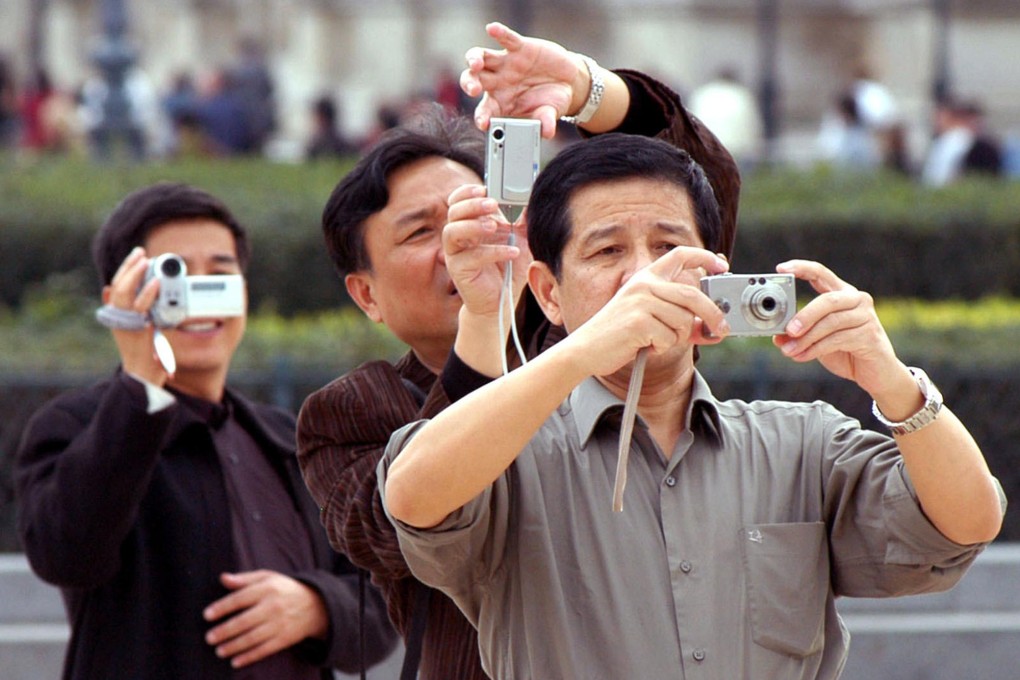 Chinese tourists take photographs during a visit to Paris. Photo: Bloomberg