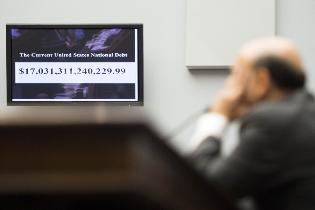 Ben Bernanke testifies in front of a screen showing tallying the US national debt. Photo: AFP