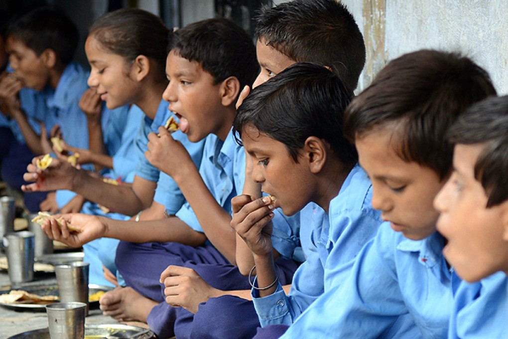 Indian children eat their free lunch at a school in Amritsar yesterday