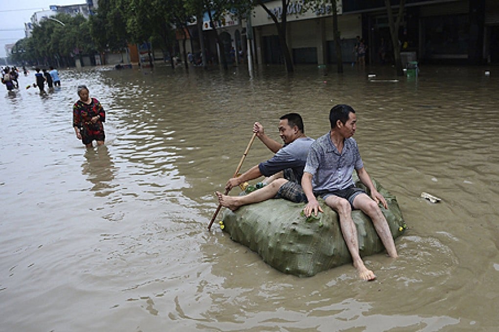 People sit on a makeshift raft made with a bag of plastic bottles on a flooded street in Jintang county, Chengdu, Sichuan province, on July 11. Photo: Reuters