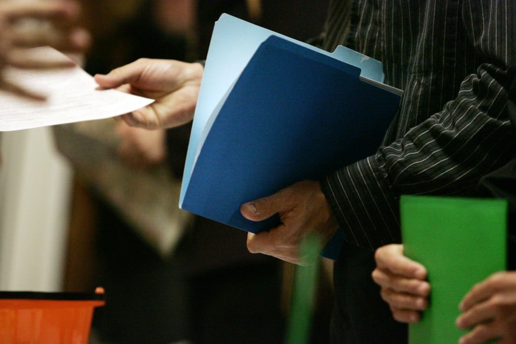 A job seeker hands a resume to a representative during a job fair. Photo: Bloomberg