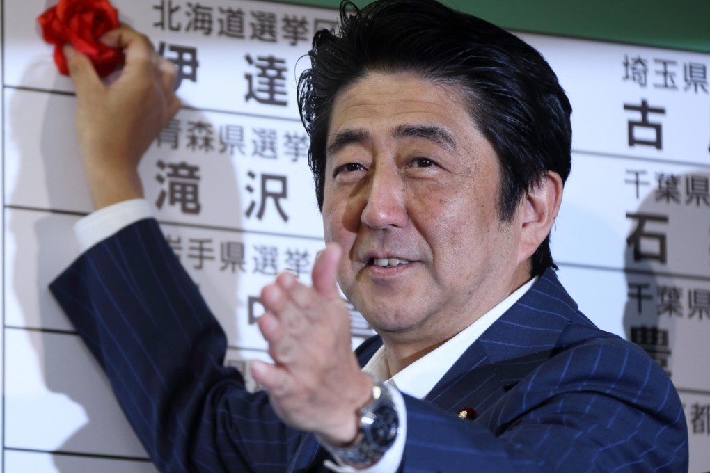 Shinzo Abe places a red paper rose on an LDP candidate's name at the party HQ yesterday to indicate victory in the polls. Photo: Bloomberg