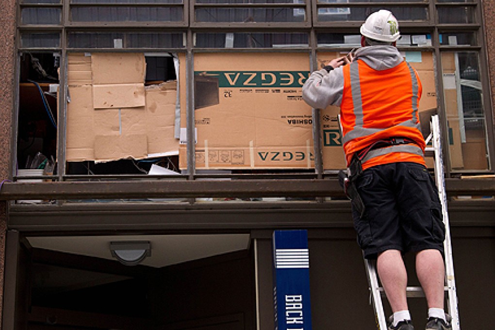 A glazier repairs broken windows in Wellington on Monday. Photo: AFP