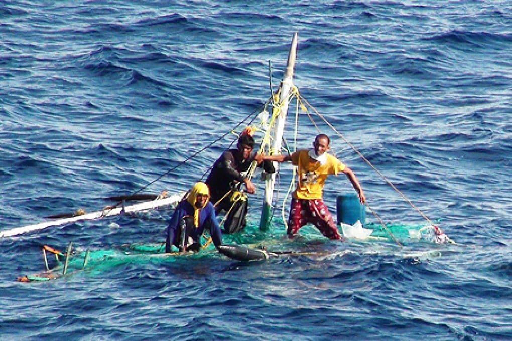 Three Filipino fishermen hold on their small boat on the sea near Kaohsiung city in southern Taiwan. Photo: AFP