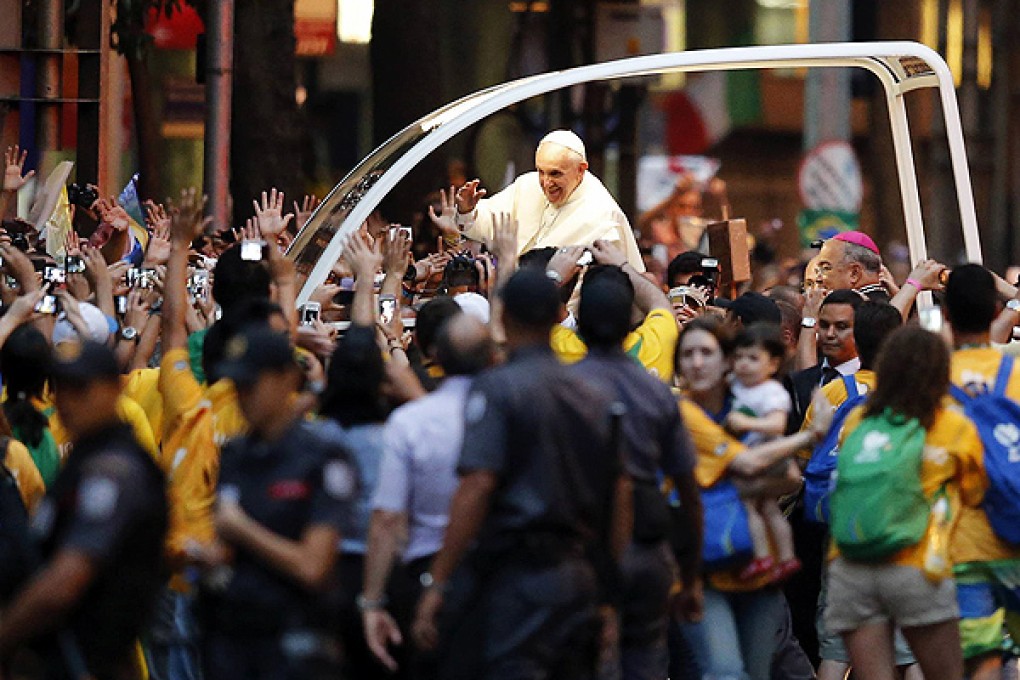 Pope Francis kisses a baby while greeting crowds in Rio de Janeiro. Photo: Reuters
