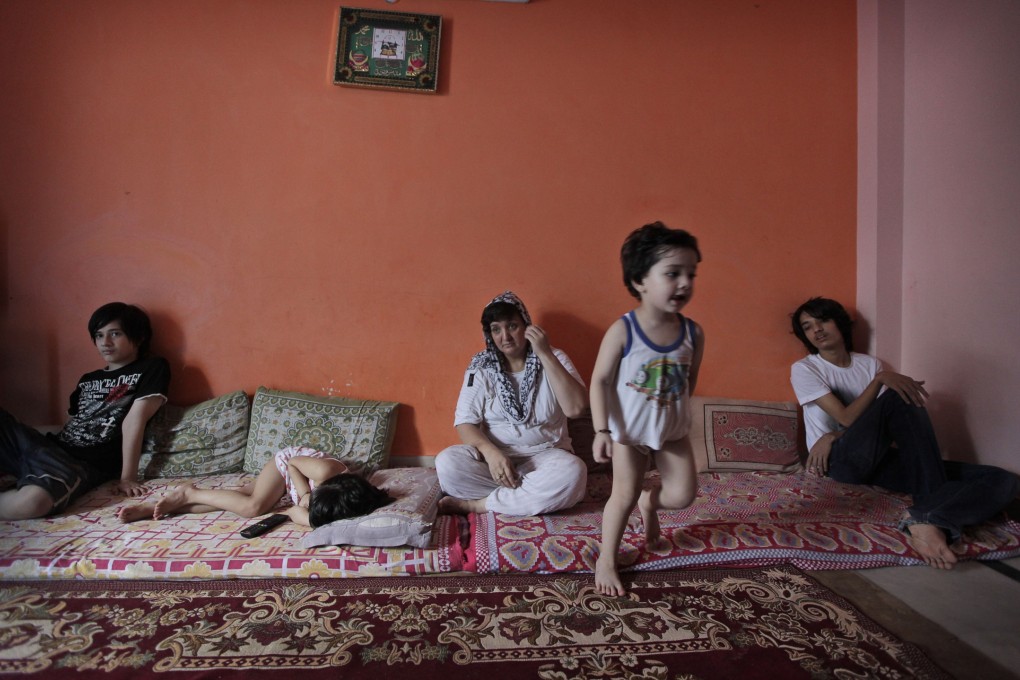 Two-year-old Hussain runs in the family's small flat as his mother Sharifa Jan, centre, and siblings sit on mattresses in Bhogal in New Delhi, India. Jan and her children fled Afghanistan for India last year. Photo: AP