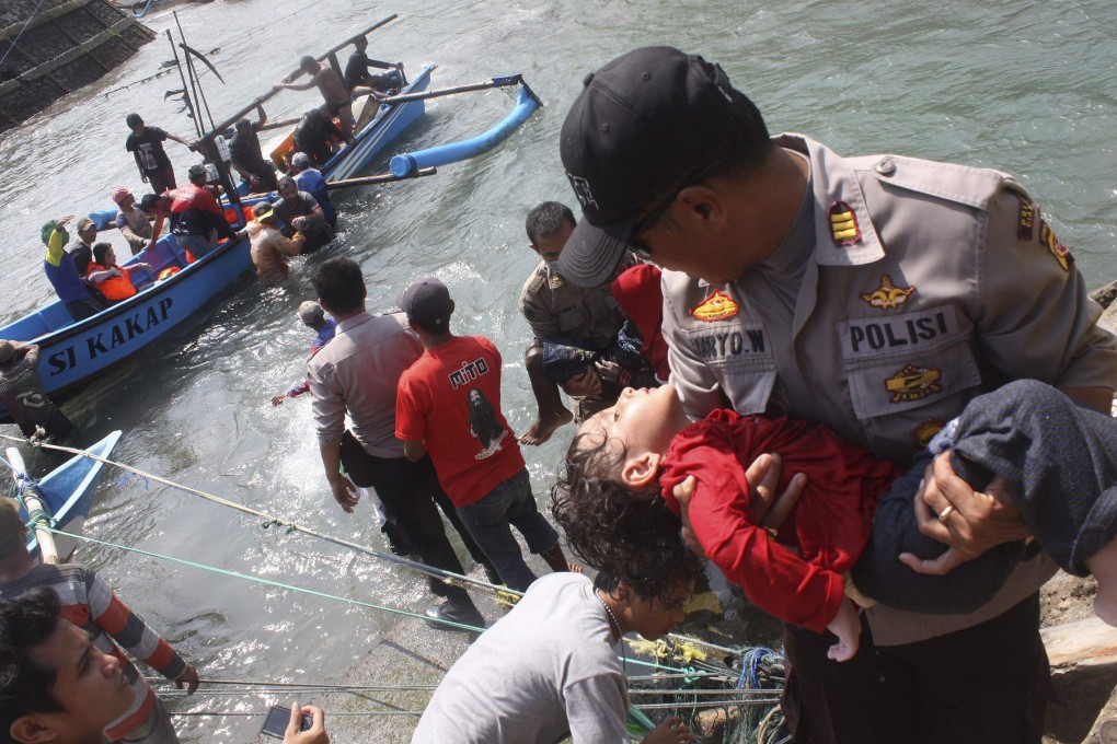 A police officer carries an unconscious child from the boat that capsized after hitting a reef off the coast of Sukapura, in Cianjur. Photo: Reuters