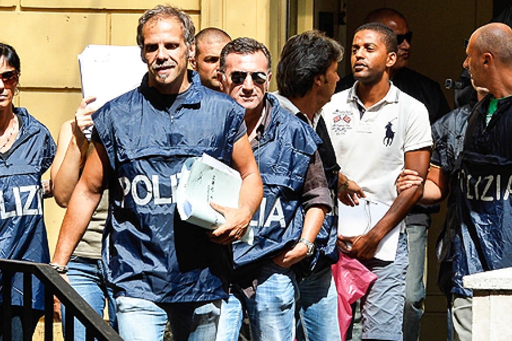 Italian Eugenio Ferrano (second right), one of 51 people arrested for organised crime in Ostia, 30 km from Rome, is taken away by policemen at the Italian police Headquarter, in central Rome, on Friday. Photo: AFP