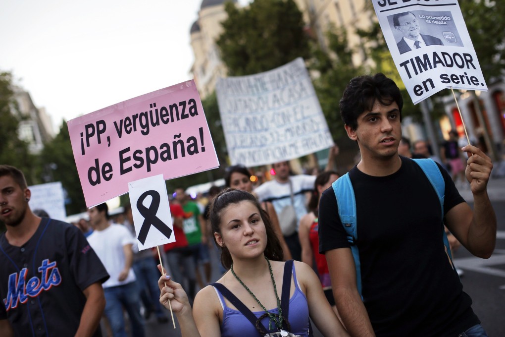 A demonstrator holds a sign with a black ribbon hanging from it in memory of the victims of the train crash in Santiago de Compostela. Photo: Reuters
