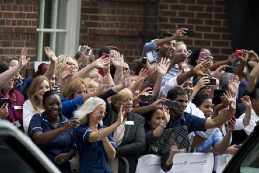 People in the crowd cheer and reach out to take pictures of the royal couple and their new born son outside St Mary's Hospital in London. Photo: AFP
