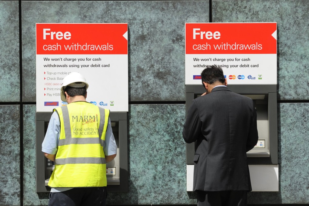 Customers use ATMs at a branch of HSBC bank in London. Photo: Bloomberg