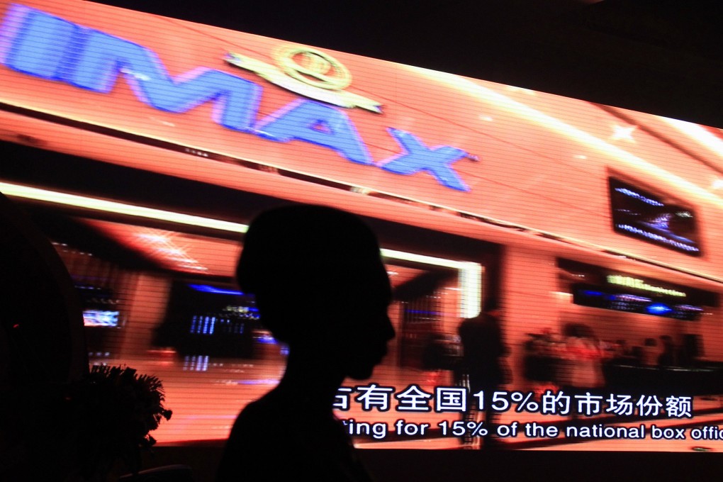 A model stands in front of a video presentation before the start of an official signing ceremony between Wanda Group, one of China's largest theatre owners, and AMC Entertainment, the world's largest operator of IMAX screens, in Beijing. Photo: Reuters