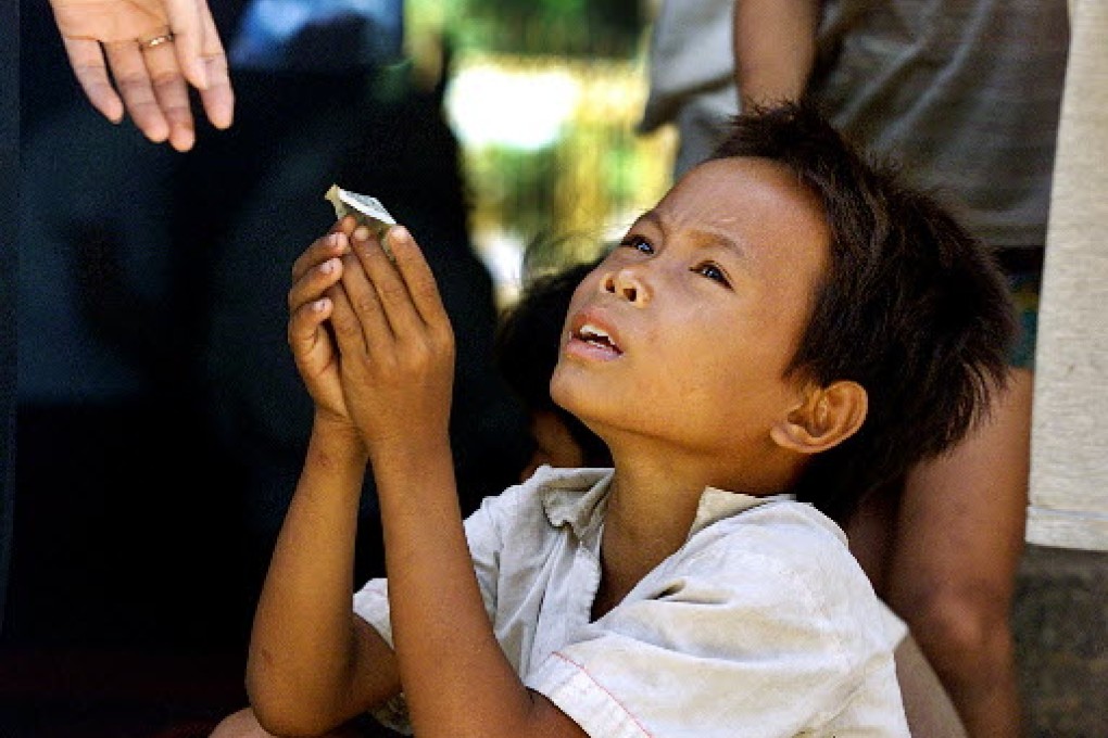 Cambodian street child accepts a small amount of change from a visitor. Photo: AP