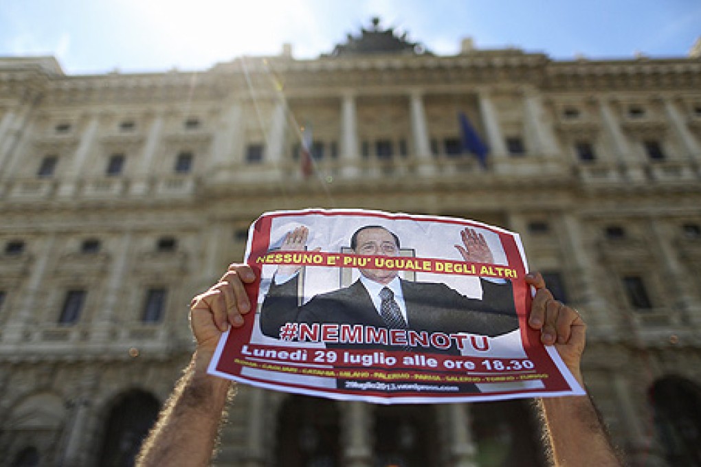 A man holds up a picture of former Italian Prime Minister Silvio Berlusconi as he protests in front of Italy's supreme court building in Rome on Tuesday. Photo: Reuters