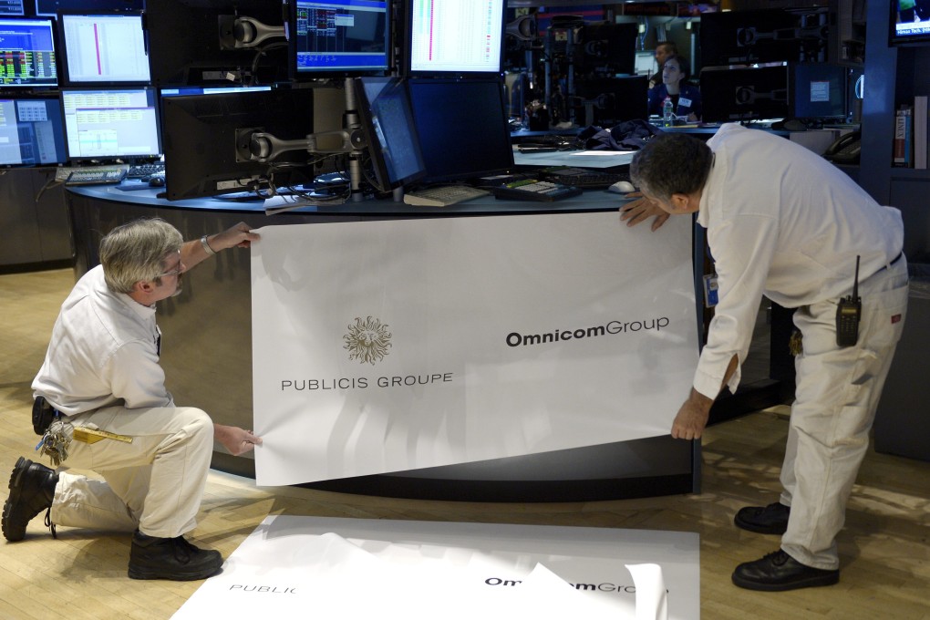 Workers at the New York Stock Exchange prepare signage to mark the merger of Omnicom and Publicis. Photo: EPA
