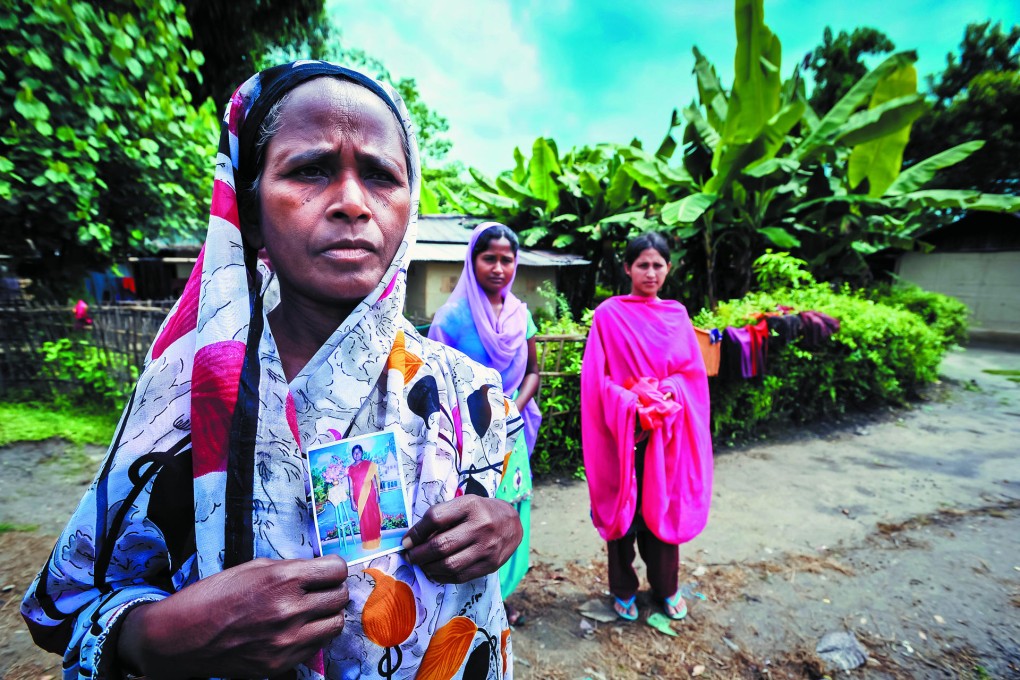 Saphira Khatun holds a picture of her missing daughter, Minu Begum, who disappeared four years ago, aged 12, from their village in Lakhimpur district, Assam. Standing behind Saphira are her two other daughters, Nadira (right) and Munu.