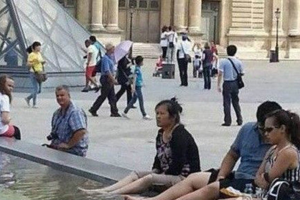 An Asian woman dips her feet in the Louvre fountain in Paris. Photo: Screenshot via Weibo