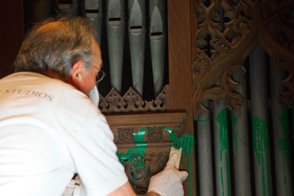 A worker cleans green paint from the organ in the Bethlehem Chapel at the National Cathedral on Tuesday in Washington, D.C. Photo: AFP