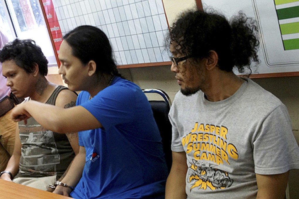 Thai musicians from left, Sathit Somsa, 40, Ratikorn Romin, 27, and Noppanant Yoddecha, 26, are handcuffed and interrogated at Krabi police station. Photo: AP