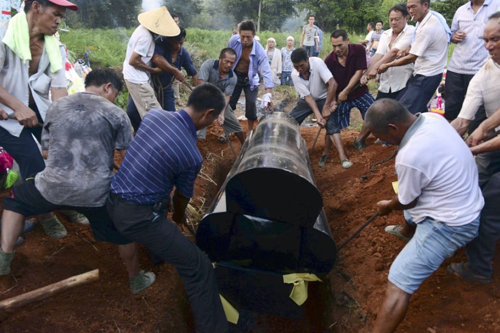 Relatives and villagers place the coffin of 56-year-old farmer Deng Zhengjia into a pit during a funeral in Linwu county. Photo: Reuters