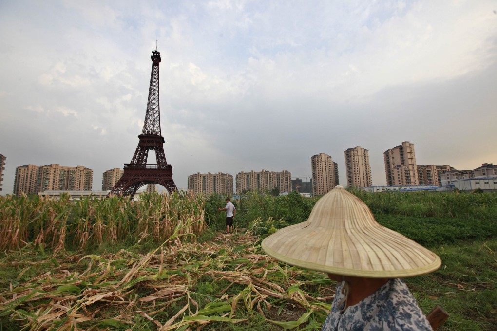 A farmer walks through a field near a replica of the Eiffel Tower at the Tianducheng development in Hangzhou, Zhejiang Province on Thursday. Photo: Reuters