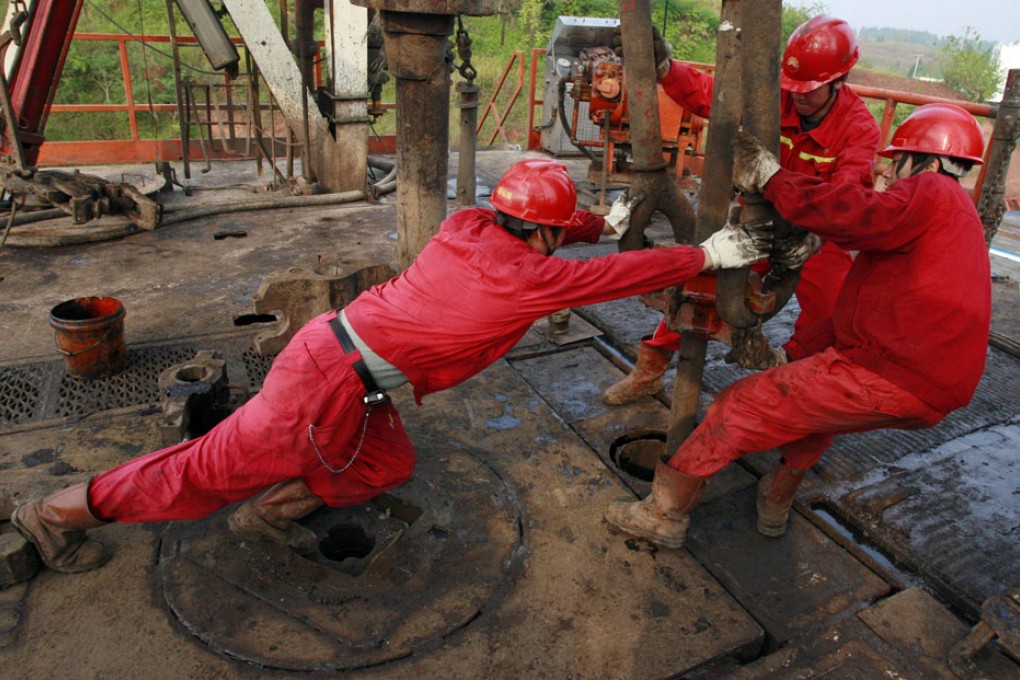 Labourers work at a well head in an oil field in Sichuan. Photo: Reuters