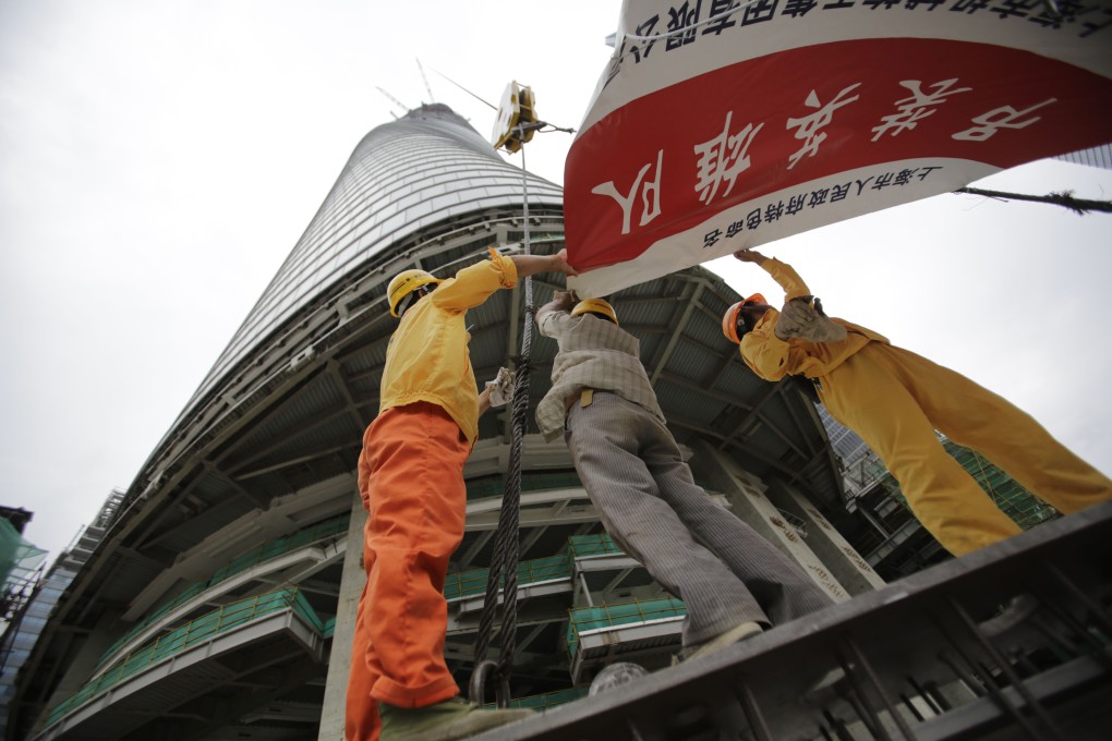 Workers arrange the banner at the bottom of the Shanghai Tower under construction in Shanghai. Photo: AP