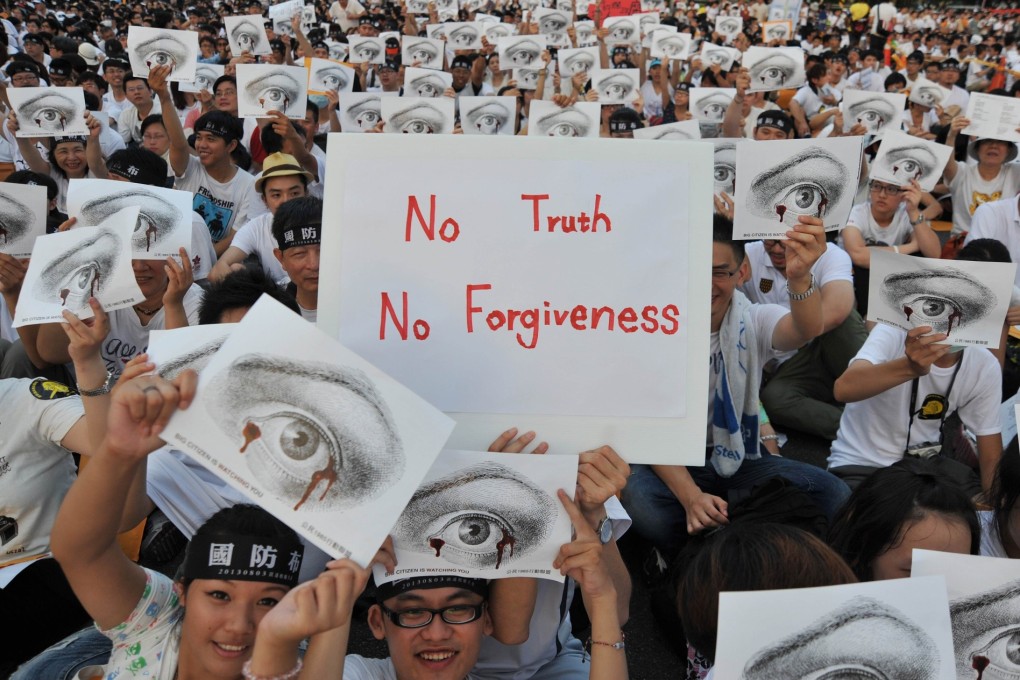 Protesters hold placards as they sit during an anti-military rally in front of Taiwan's presidential office in Taipei on Saturday. Photo: AFP