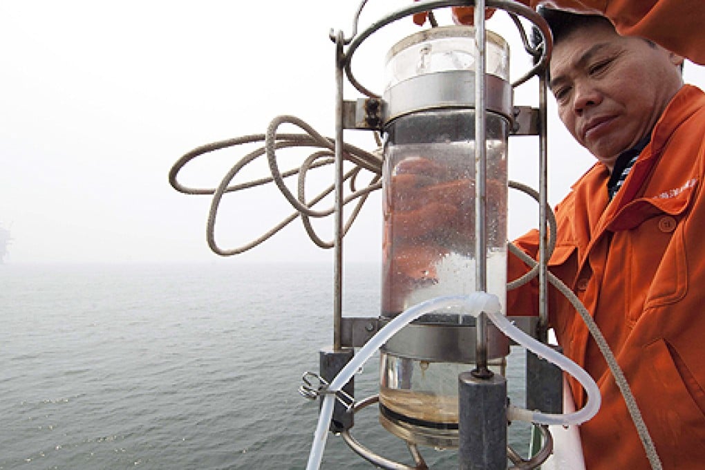 A scientist takes a water sample in north China's Bohai Bai, in July 2011, near two oilfield platforms that were estimated to have leaked 240 cubic metres of oil in June 2011. Photo: Xinhua