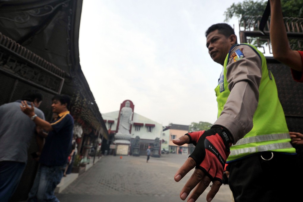 A police officer is seen outside the door of the Ekayana Buddhist temple. Photo: Xinhua