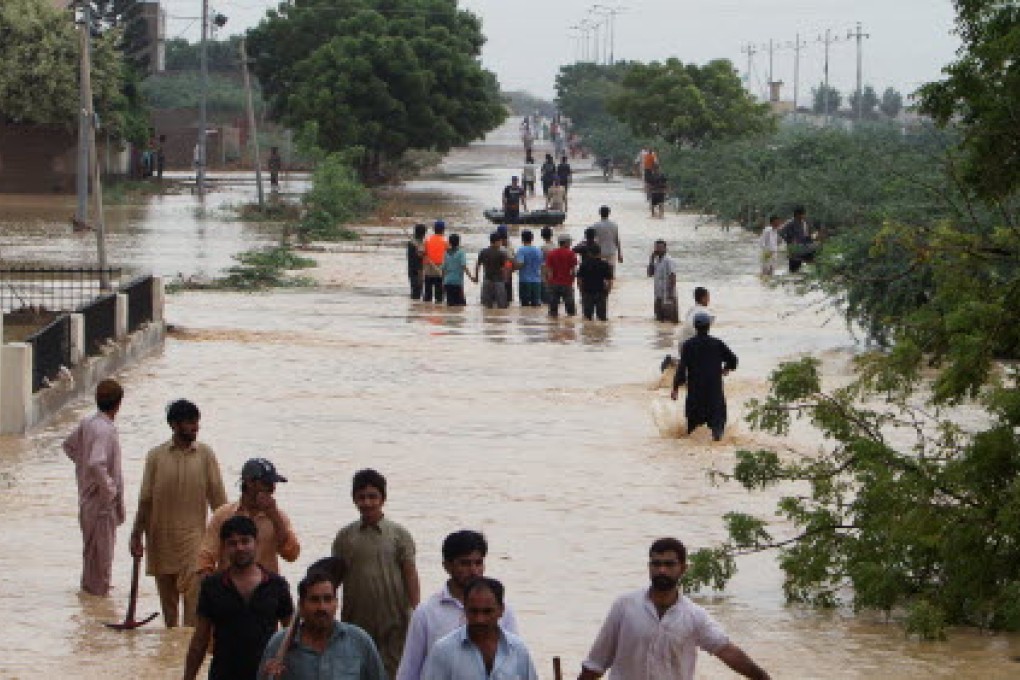 People wade through flooded road caused by heavy rains on the outskirts of Karachi. Photo: AP