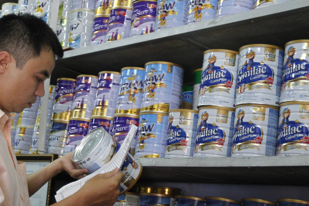 An Abbott Laboratories sales staff checks the serial number of a powder milk tin during a production recall at a milk shop outside Hanoi. Photo: Reuters