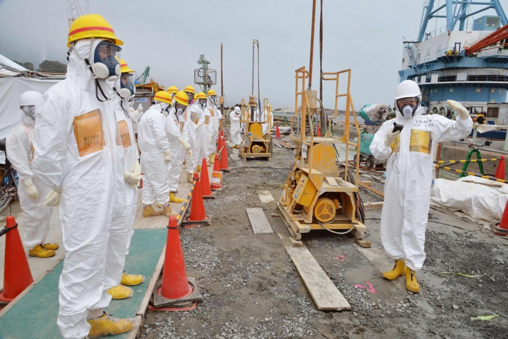 Members of a Fukushima prefecture panel inspect construction of a shore barrier at the nuclear power plant. Photo: Reuters