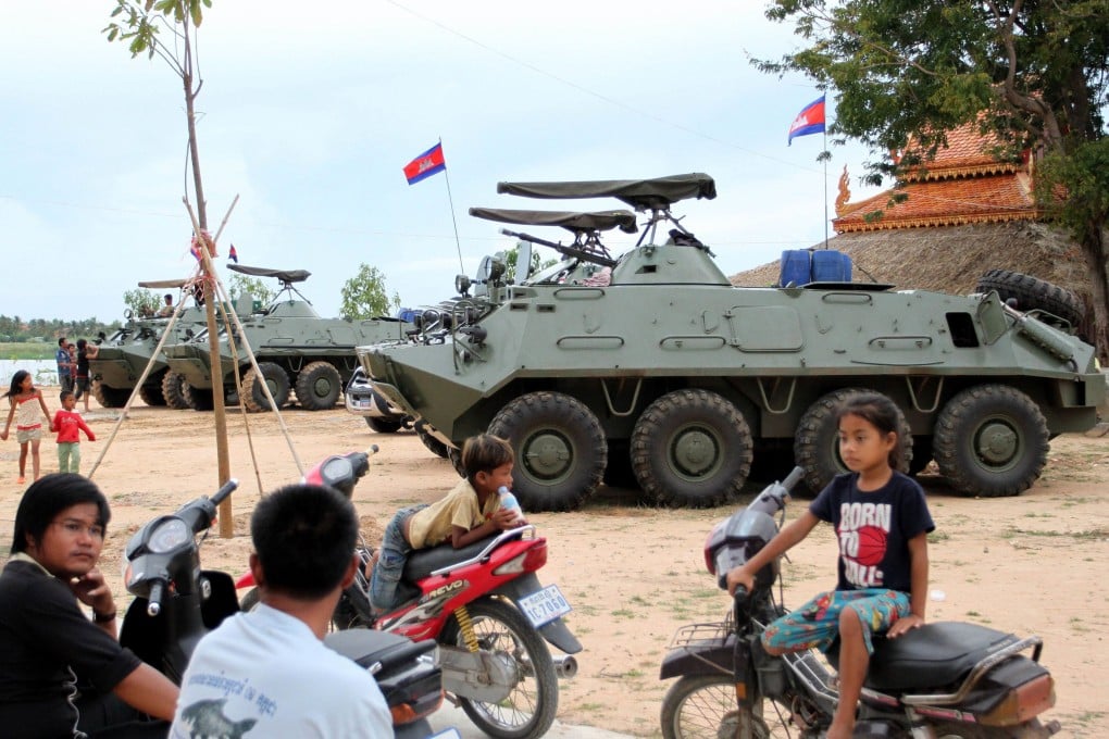 Cambodian children sitting on motorbikes near armored personnel carriers on the outskirts of Phnom Penh. Photo: AFP