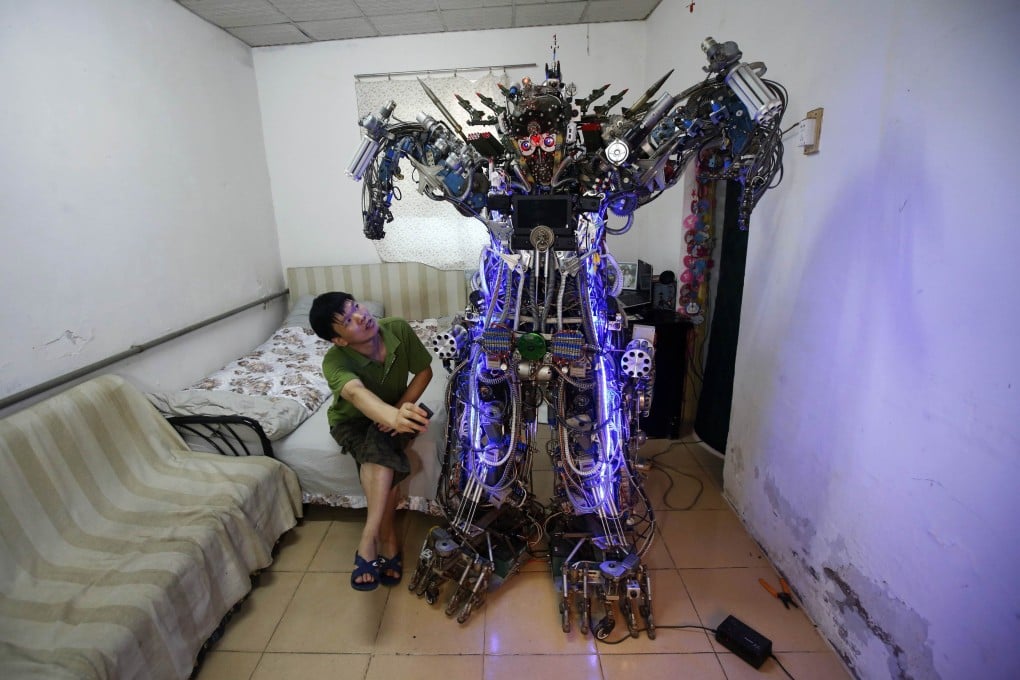 Chinese inventor Tao controls his self-made humanoid robot with a remote controller as he poses with it at his house in Beijing. Photo: Reuters