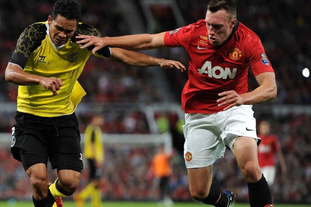 Manchester United's Phil Jones tangles with Sevilla striker Carlos Bacca in a friendly won 3-1 by the visitors at Old Trafford. Photo: AFP