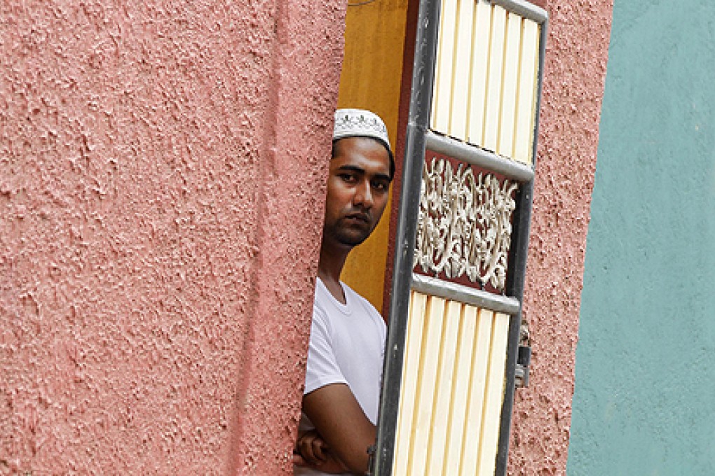 A Muslim man peeps through a gate at a vandalized mosque in Colombo on Sunday. Photo: AP