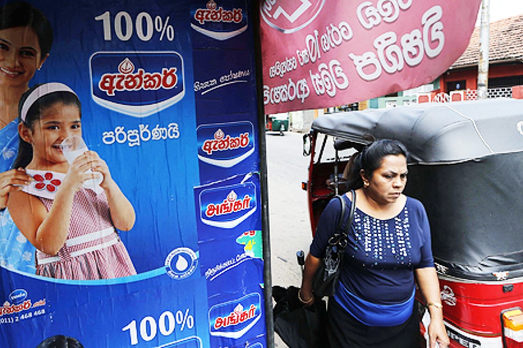 A Sri Lankan woman walks past an advertisement of a Fonterra product in Colombo, Sri Lanka. Photo: AP