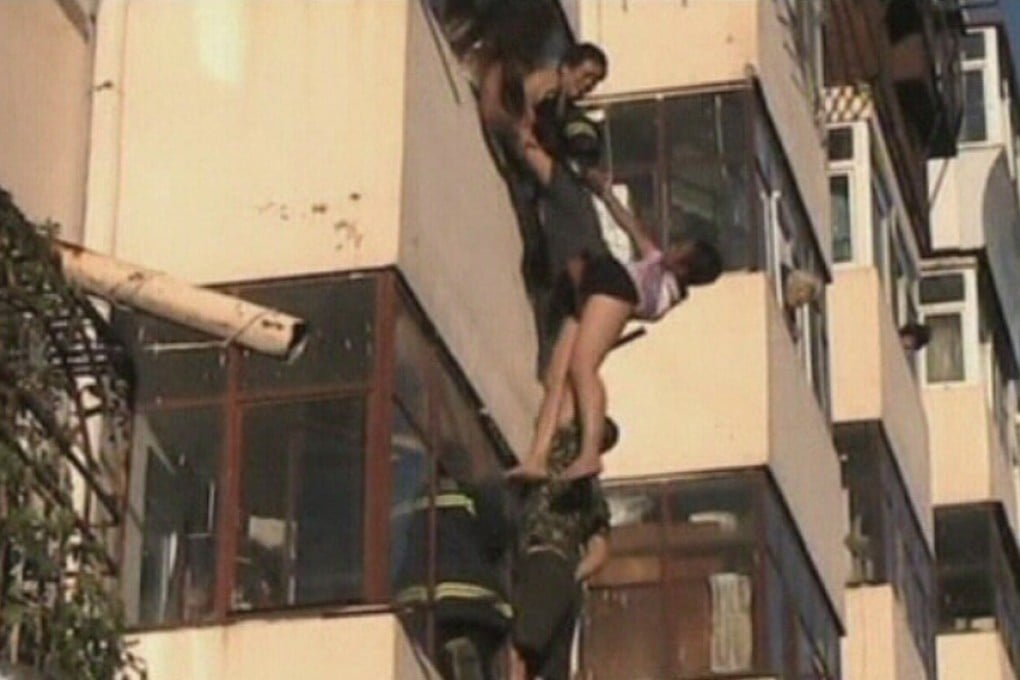 The woman dangles from the fifth floor of the balcony. Photo: Reuters