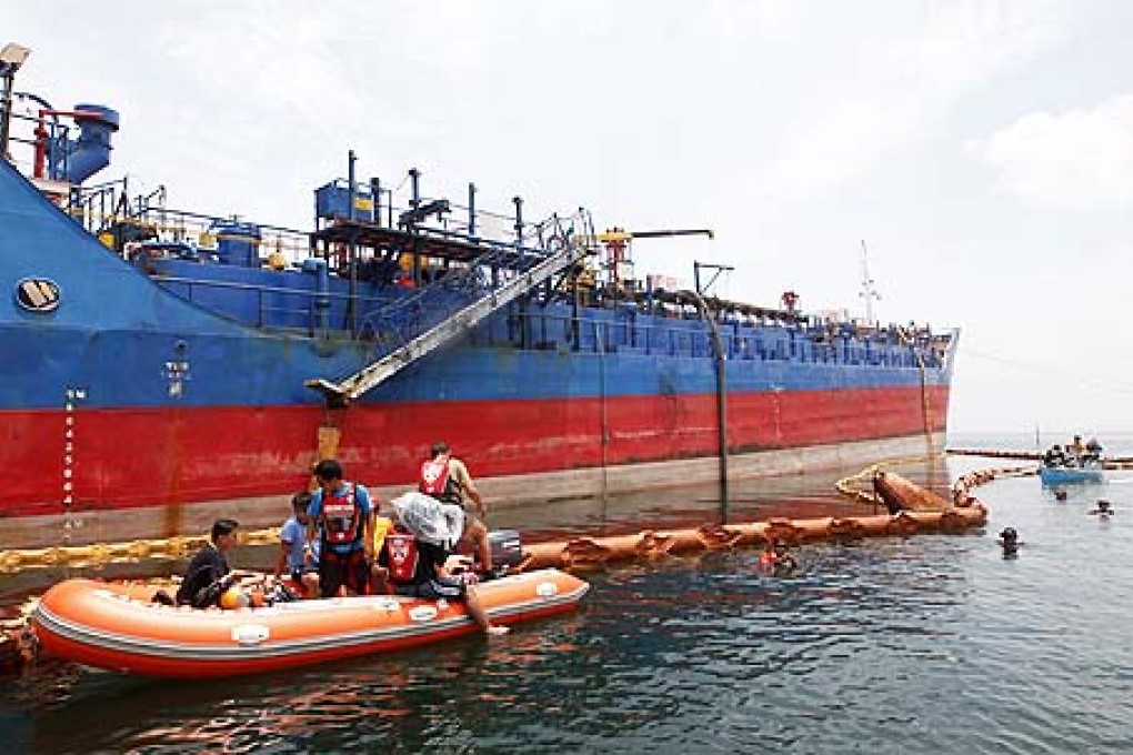 Divers prepare to descend into waters in front of an oil tanker surrounded by oil containment booms off the shore of Cavite province, on Saturday, to determine if a leaking pipeline could be resposible for the oil spill. Photo: EPA
