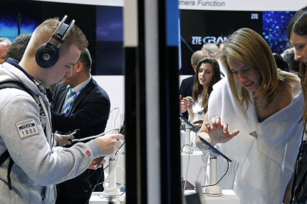 Visitors look at mobile devices at ZTE's booth at the Mobile World Congress in Barcelona in February. Photo: Reuters