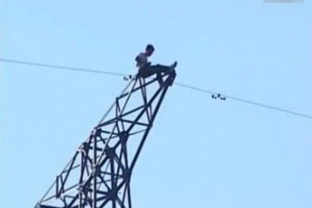 Photo shows the man sitting on top of a tower with high voltage electrical wires before the deadly accident occured. Photo: Xinhua